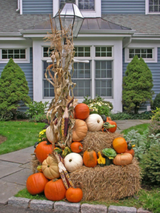 pumpkins and fall decor stacked on straw bales in front lawn